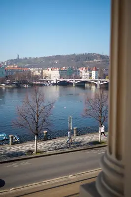 a view of a river with a bridge in the background at Rašínovo nábřeží - Riverside Residence in Prague