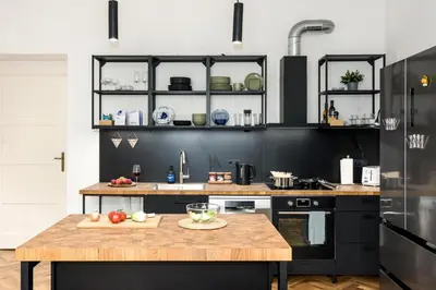 a kitchen with black cabinets and a wooden table at Prague Days - One-bedroom Apartment with Balcony and Workspace in Vinohrady in Prague