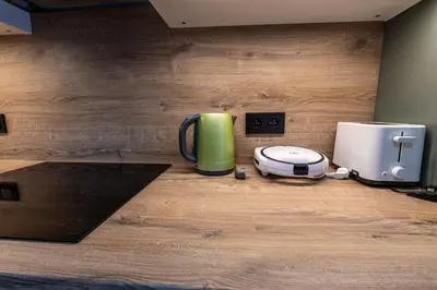 a green coffee mug sitting on the floor next to a toaster at Spoon Apartment Prague 1A in Prague