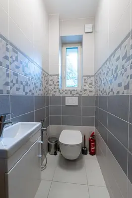 a bathroom with a toilet and a sink and a window at Spoon Apartment Prague 1A in Prague