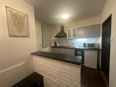 a kitchen with white cabinets and a black counter top at Budget Dlouha Apartment in Prague
