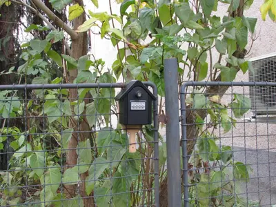 a parking meter on a fence next to a tree at PragueCityApartment in Prague