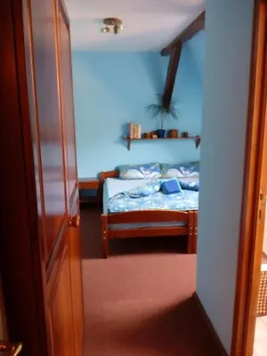a bedroom with a bed with a blue wall at Penzion Hájovna U Dubu in Karlštejn