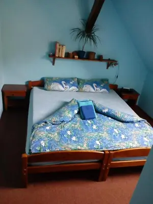 a bed with a blue comforter with a book on it at Penzion Hájovna U Dubu in Karlštejn