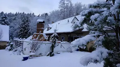 a house with snow on the roof of it at Penzion Hájovna U Dubu in Karlštejn