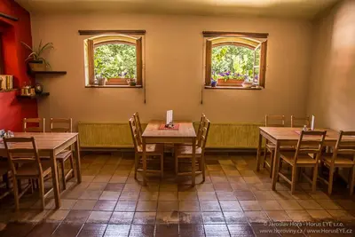 a restaurant with tables and chairs and two windows at Penzion Hájovna U Dubu in Karlštejn