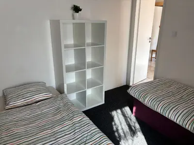a bedroom with two beds and a white book shelf at Ubytování Hoštka in Hošťka