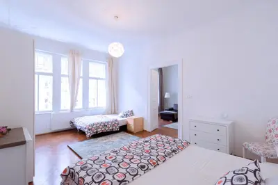 a white bedroom with a bed and a chair at Apartments Vezenska in Prague