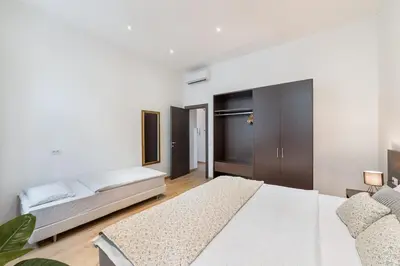 a white bedroom with a bed and a couch at Premiere Dubcek Apartment in Prague