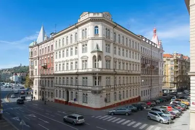a large white building with cars parked in a parking lot at Premiere Dubcek Apartment in Prague