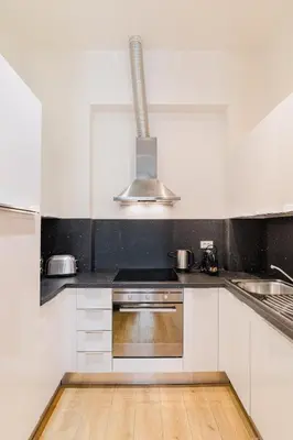 a kitchen with white cabinets and a stove top oven at Premiere Dubcek Apartment in Prague