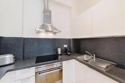 a kitchen with white cabinets and a sink at Premiere Dubcek Apartment in Prague