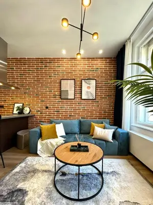 a living room with a blue couch and a brick wall at Rentero modern Apartment, 10 minutes Charles bridge, Prague in Prague