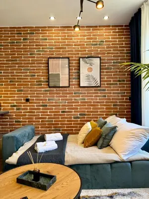 a living room with a couch and a brick wall at Rentero modern Apartment, 10 minutes Charles bridge, Prague in Prague