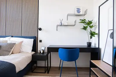 a bedroom with a desk and a bed with a blue chair at Rentero modern Apartment, 10 minutes Charles bridge, Prague in Prague