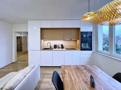 a kitchen with white cabinets and a wooden table at Jana's WOW apt, 3 room, free parking, 15'Airpt, 25'City in Prague