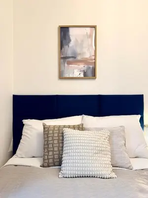 a bed with a blue head board with pillows on it at Rentero Royal blue Wenceslas Apartment, Prague in Prague