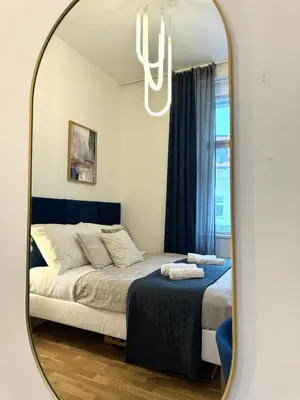 a bedroom with a bed and a mirror at Rentero Royal blue Wenceslas Apartment, Prague in Prague