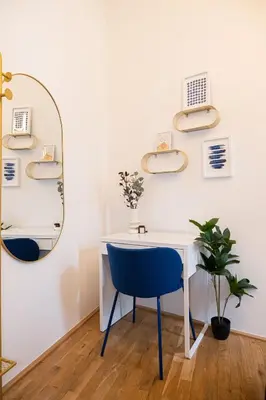 a white desk with a blue chair and a mirror at Rentero Royal blue Wenceslas Apartment, Prague in Prague