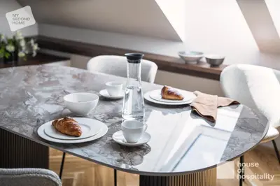 a table with plates of croissants and a glass bottle at MY SECOND HOME by House of Hospitality in Prague