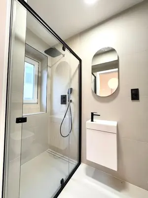 a bathroom with a shower and a sink and a mirror at Rentero Golden Wabi-Sabi Apartment, Prague in Prague