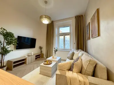 a living room with a couch and a tv at Rentero Golden Wabi-Sabi Apartment, Prague in Prague