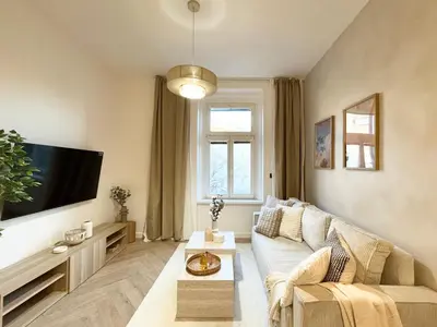 a living room with a couch and a tv at Rentero Golden Wabi-Sabi Apartment, Prague in Prague