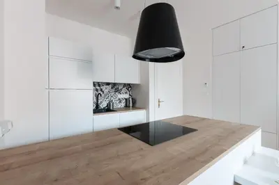 a kitchen with white cabinets and a black pendant light at Prague Days - Art Deco Studio near Main Train Station in Prague