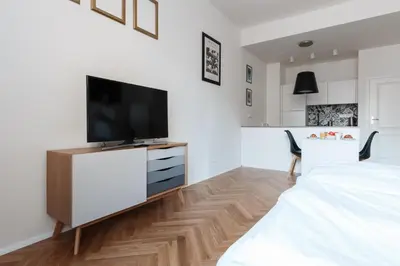 a white bedroom with a television on a dresser at Prague Days - Art Deco Studio near Main Train Station in Prague