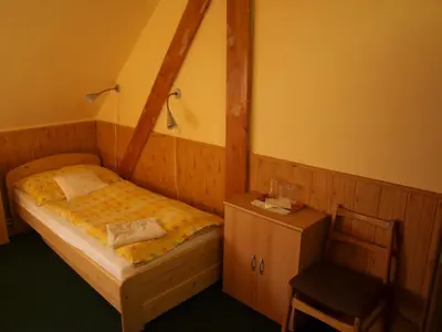 a small bedroom with a bed and a chair at Hotel Kormoran in Zlenice