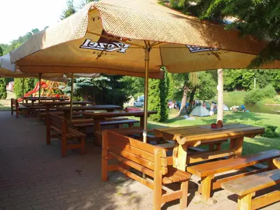 a group of wooden tables and benches with an umbrella at Hotel Kormoran in Zlenice