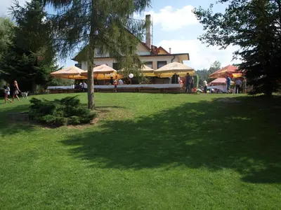 a large building with a tree in a park at Hotel Kormoran in Zlenice