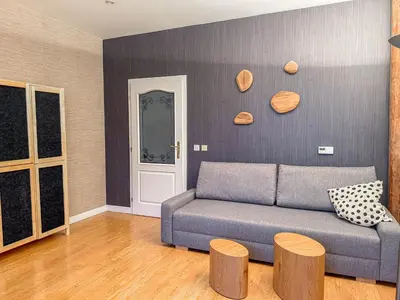 a living room with a blue couch and wooden stools at Radost Residence The Heart of Unique Living in Prague