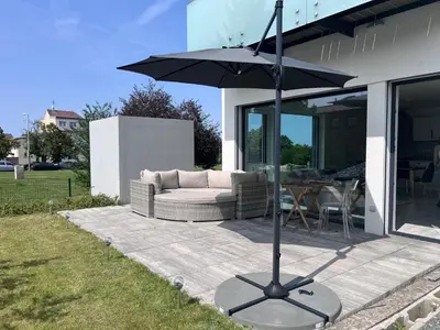 a patio with a couch and an umbrella at Modern apartment close to Tram and Airport, free parking in Prague