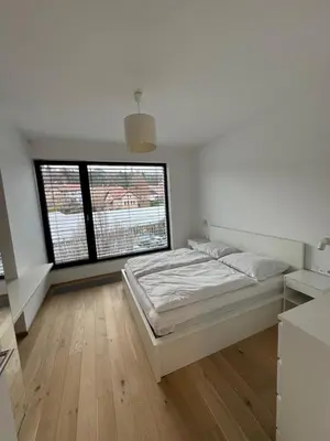 a white bedroom with a bed and two windows at Apartmán v nové rezidenci in Prague