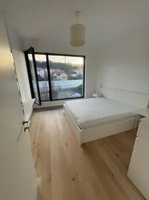 a bedroom with a white bed and a large window at Apartmán v nové rezidenci in Prague