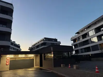 a parking lot in front of two tall buildings at Apartmán v nové rezidenci in Prague