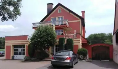 a car parked in front of a red house at Penzion Červený mlýn in Rakovník
