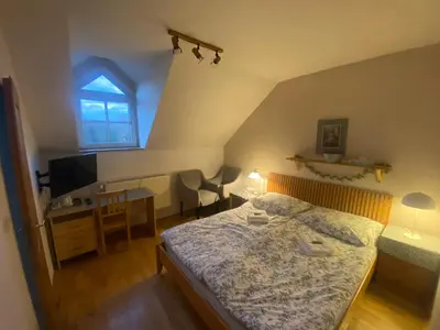 a bedroom with a bed and a desk and a tv at Penzion Červený mlýn in Rakovník