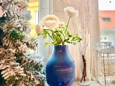 a blue vase with flowers in it next to a christmas tree at Ruby Prague Apartment in Prague