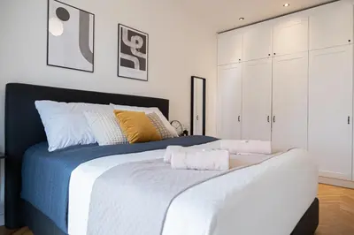 a bedroom with a large bed with white cabinets at Rentero Spacious Apartment near Prague Castle in Prague
