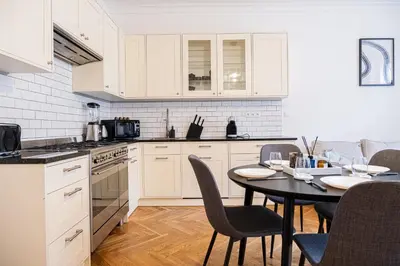 a kitchen with white cabinets and a table with chairs at Rentero Spacious Apartment near Prague Castle in Prague