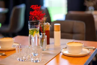 a table with glasses and a vase with flowers on it at Hotel NOBILIS - Mladá Boleslav in Bradlec
