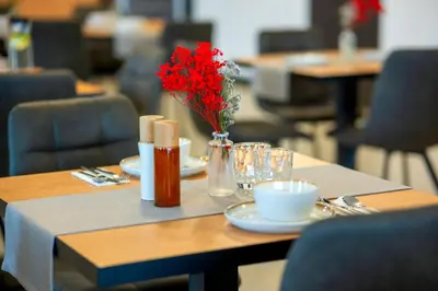 a table with a vase of red flowers on it at Hotel NOBILIS - Mladá Boleslav in Bradlec