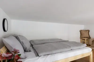 a white bedroom with a bed with gray sheets at Stay2gether - Vacation at grandma's in Prague