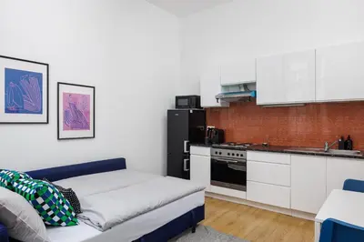 a kitchen with white cabinets and a couch in a room at Stay2gether - Grandma's Blues in Prague