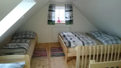 two beds in a attic room with a window at Apartmány Vilekula Sázava in Sázava