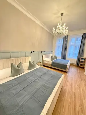 a large bedroom with two beds and a chandelier at Stunning apartment in middle of Wenceslas Square in Prague