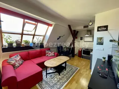 a living room with a red couch and a table at Podkrovní hnízdečko in Prague