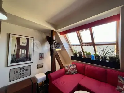 a living room with a red couch and two windows at Podkrovní hnízdečko in Prague